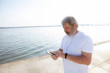 Nehir kenarında kol bandı veya fitness Tracker ile Runner olarak Kıdemli adam