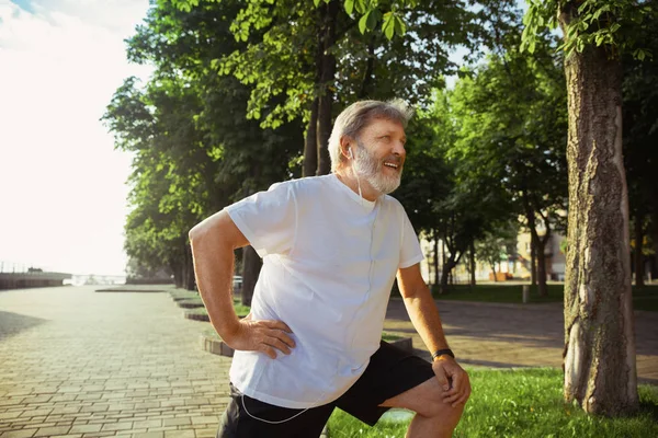 Senior man as runner with armband or fitness tracker at the citys street