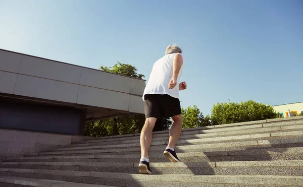 Homem sênior como corredor com braçadeira ou rastreador de fitness na rua citys — Fotografia de Stock