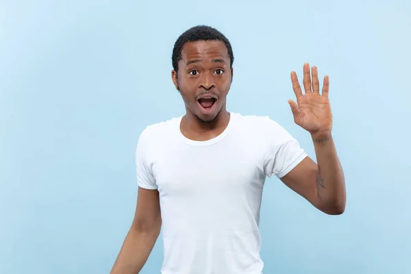 Halblanges Nahaufnahme-Porträt eines jungen Mannes auf blauem Hintergrund. — Stockfoto