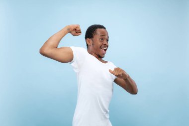 Yarı uzunlukta mavi arka planda genç adamın portre yakın.