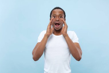 Yarı uzunlukta mavi arka planda genç adamın portre yakın.