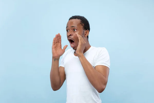 Halblanges Nahaufnahme-Porträt eines jungen Mannes auf blauem Hintergrund. — Stockfoto