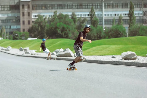 Skateboarders doing a trick at the citys street in sunny day — Stock Photo, Image
