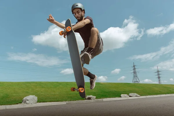 Skateboarder doing a trick at the citys street in sunny day — Stock Photo, Image