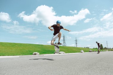 Skateboarders güneşli bir gün içinde kentin sokakta bir hüner yapıyor