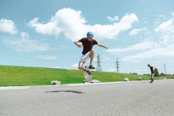 Skateboarders doing a trick at the citys street in sunny day — Stock Photo, Image