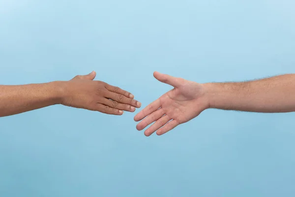 Close up shot of human holding hands isolated on blue studio background.