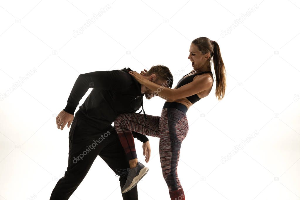 Man and woman fighting in studio, womens self-defense concept