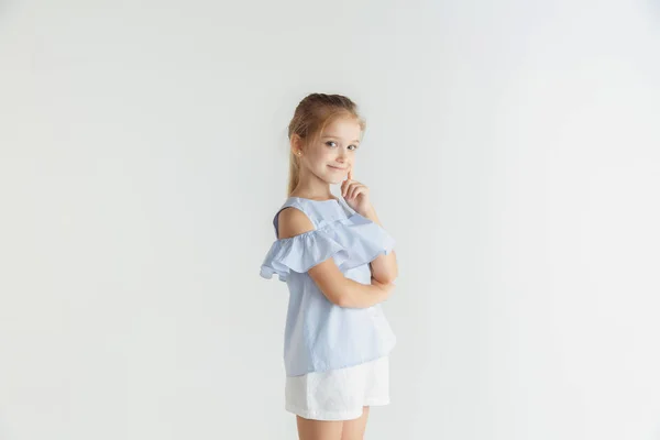 Kleines lächelndes Mädchen posiert in lässiger Kleidung auf weißem Studiohintergrund — Stockfoto