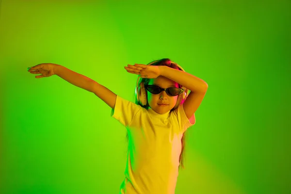 Retrato de niña en auriculares sobre fondo verde en luz de neón — Foto de Stock