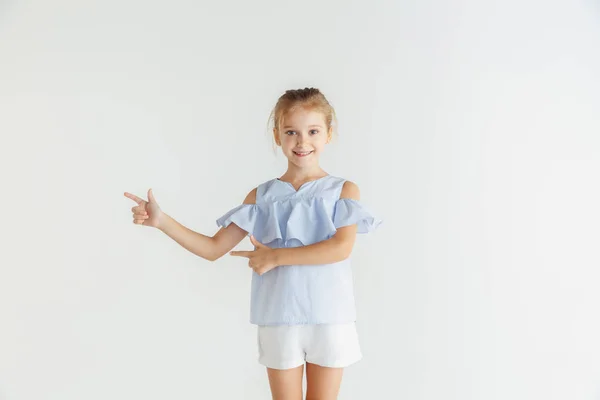 Маленька усміхнена дівчинка позує в повсякденному одязі на білому фоні студії — стокове фото