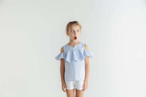 Маленька усміхнена дівчинка позує в повсякденному одязі на білому фоні студії — стокове фото