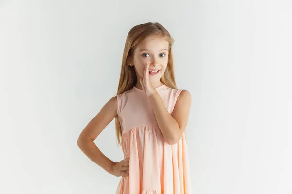 Маленькая улыбающаяся девочка позирует в платье на белом фоне студии — стоковое фото
