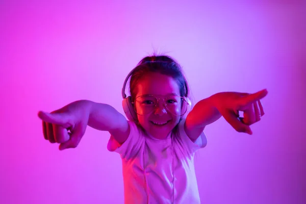 Πορτρέτο του μικρού κοριτσιού στα ακουστικά σε μωβ φόντο ντεγκραντέ στο φως νέον — Φωτογραφία Αρχείου