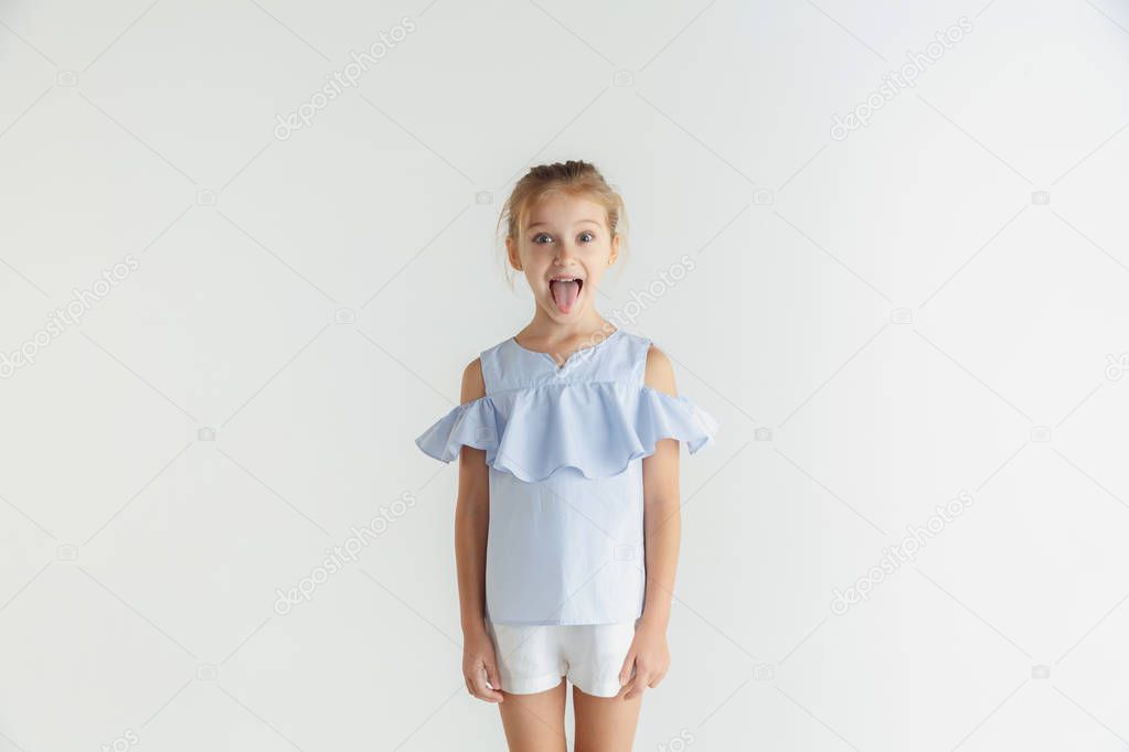 Little smiling girl posing in casual clothes on white studio background