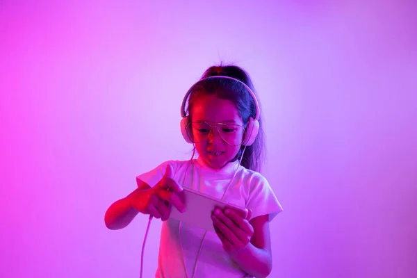 Portréja kislány fejhallgató a lila gradiens háttér Neonfény — Stock Fotó