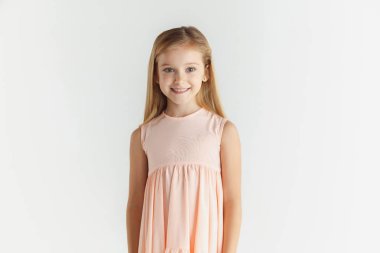 Beyaz stüdyo arka planda elbise içinde poz veren küçük gülümseyen kız