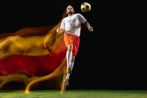男子足球运动员在混合光的黑暗背景踢球 — 图库照片