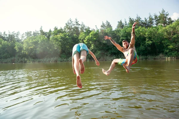 Happy friends having fun, ready to jump and swim in river