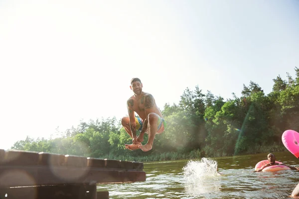 Fröhliche Gruppe von Freunden, die Spaß haben, lachen und im Fluss schwimmen — Stockfoto