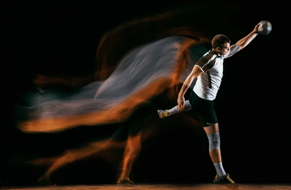 Young handball player against dark studio background in mixed light Stock Picture