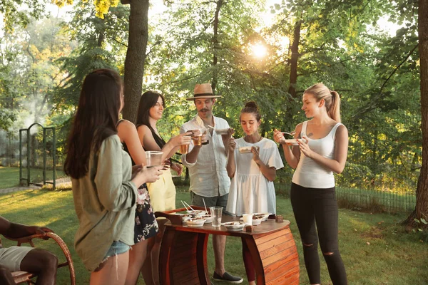 Happy Friends jedzenia i picia piwa na obiad Grill na zachodzie słońca — Zdjęcie stockowe