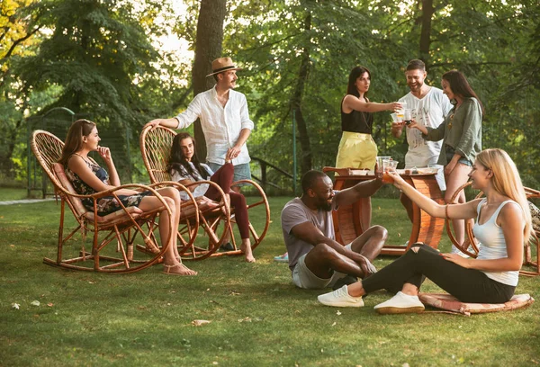 Gelukkige vrienden eten en drinken bieren bij barbecue diner op zonsondergang tijd — Stockfoto