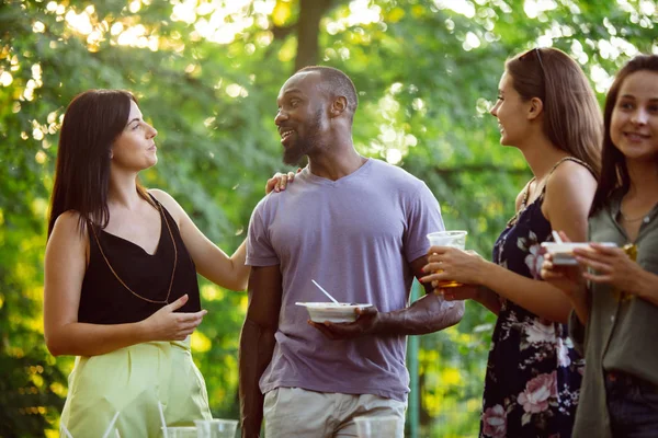 Happy friends eating and drinking beers at barbecue dinner on sunset time — Stock Photo, Image