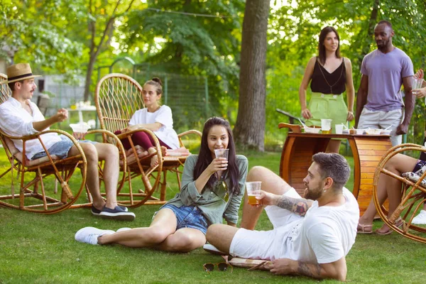 Amigos felices comiendo y bebiendo cervezas en la cena de barbacoa al atardecer — Foto de Stock