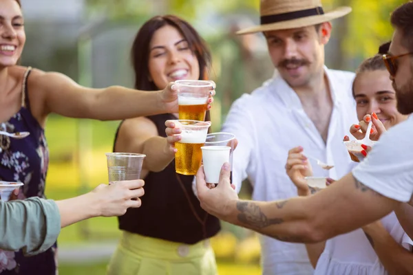 Glückliche Freunde beim Essen und Trinken von Bier beim Barbecue-Dinner bei Sonnenuntergang — Stockfoto
