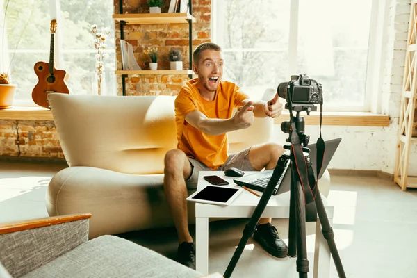 Caucasian male blogger with camera recording video review of gadgets at home