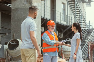 Foreman veya achitect genç bir çift için ev, ofis veya mağaza tasarım planları gösterir