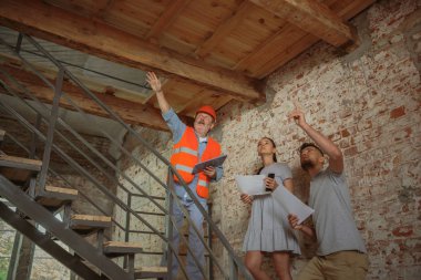 Foreman veya achitect genç bir çift için ev, ofis veya mağaza tasarım planları gösterir