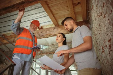 Foreman veya achitect genç bir çift için ev, ofis veya mağaza tasarım planları gösterir