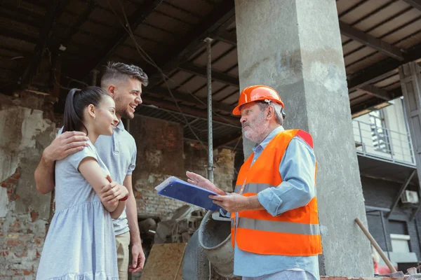 Foreman veya achitect genç bir çift için ev, ofis veya mağaza tasarım planları gösterir — Stok fotoğraf