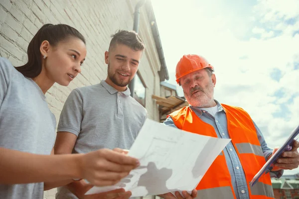 Foreman lub pasjonat pokazuje domu, biura lub sklepu plany projektowe dla młodej pary — Zdjęcie stockowe