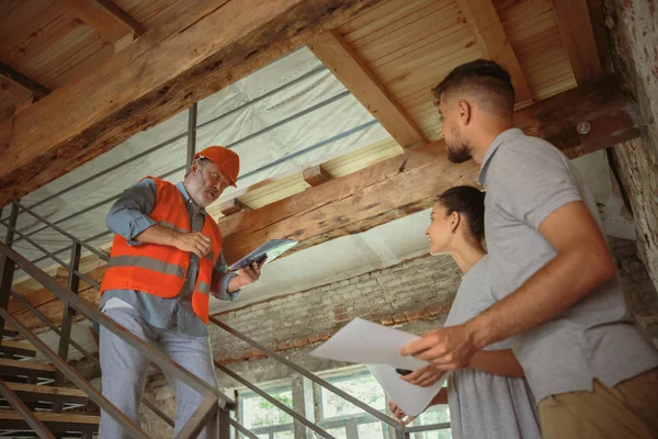 Foreman veya achitect genç bir çift için ev, ofis veya mağaza tasarım planları gösterir — Stok fotoğraf