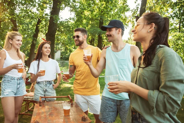 Happy friends are having beer and barbecue party at sunny day — Stock Photo, Image