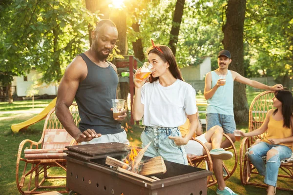 Amici felici stanno avendo birra e barbecue party nella giornata di sole — Foto Stock