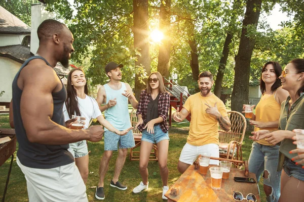 Amici felici stanno avendo birra e barbecue party nella giornata di sole — Foto Stock