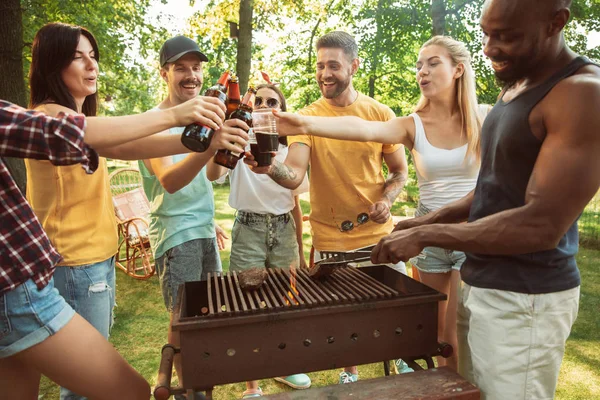 Amigos felizes estão tomando cerveja e churrasco no dia ensolarado — Fotografia de Stock