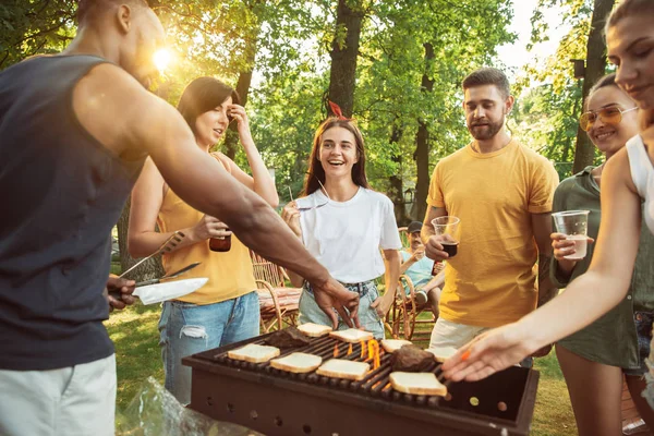 Amigos felizes estão tomando cerveja e churrasco no dia ensolarado — Fotografia de Stock