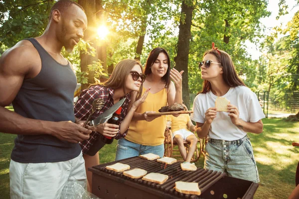 Amigos felizes estão tomando cerveja e churrasco no dia ensolarado — Fotografia de Stock