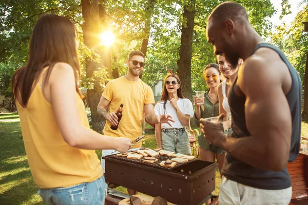 Amici felici stanno avendo birra e barbecue party nella giornata di sole — Foto Stock