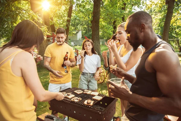 Amigos felizes estão tomando cerveja e churrasco no dia ensolarado — Fotografia de Stock