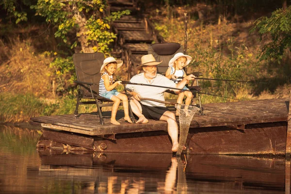 かわいい小さな女の子とそのおじいちゃんは、湖や川で釣りにしています — ストック写真