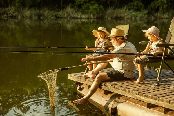 Lindas niñas y su abuelo están en la pesca en el lago o el río —  Fotos de Stock