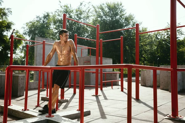 Junger muskulöser Mann beim Training draußen auf dem Spielplatz — Stockfoto