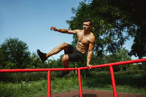 Junger muskulöser Mann beim Training draußen auf dem Spielplatz — Stockfoto